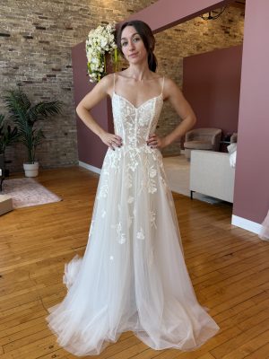 Bride wearing a white lace wedding dress with floral embroidery and a flowing train.